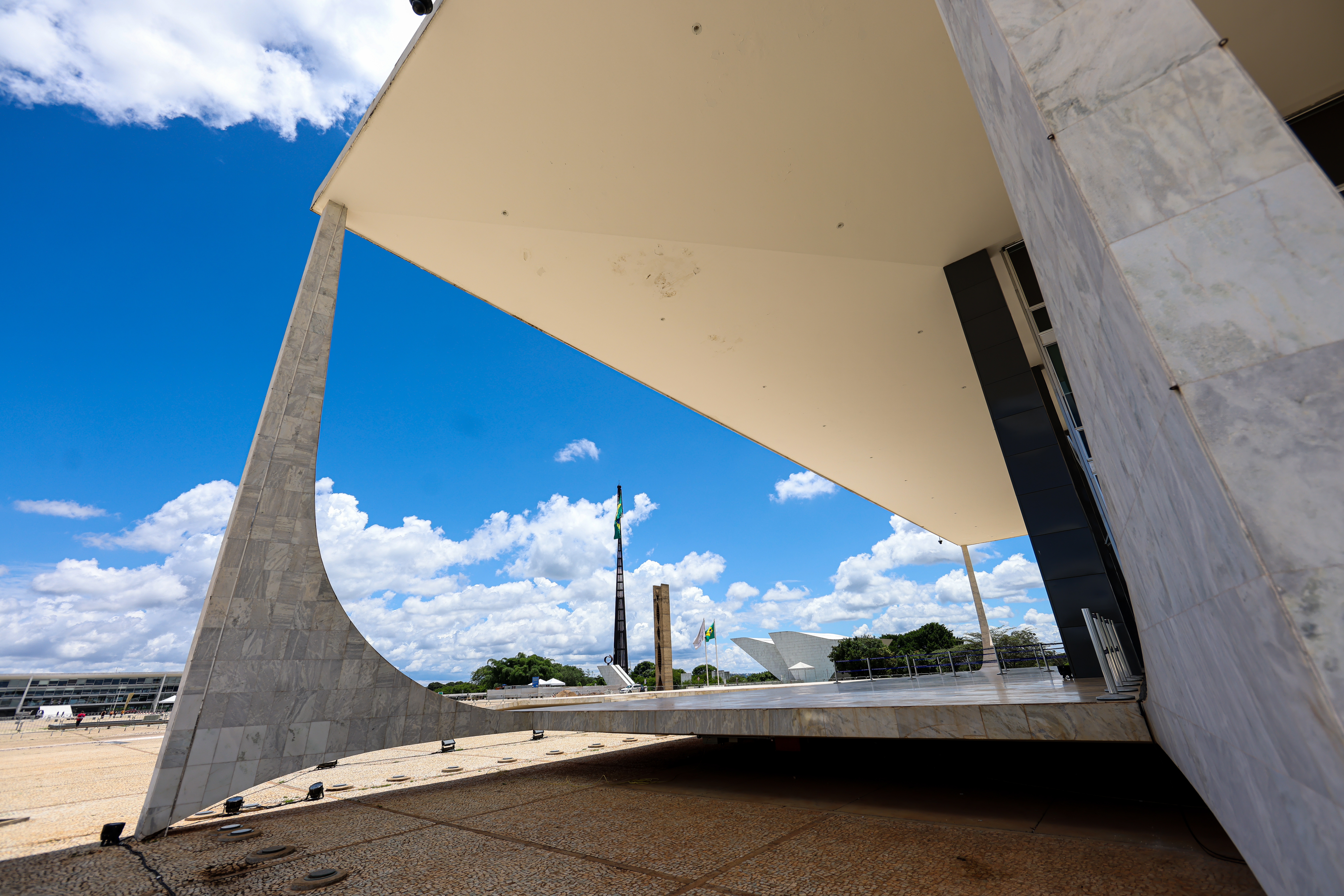 Foto em formato paisagem por dentro do prédio do Supremo Tribunal Federal e ao fundo a Praça dos Três Poderes