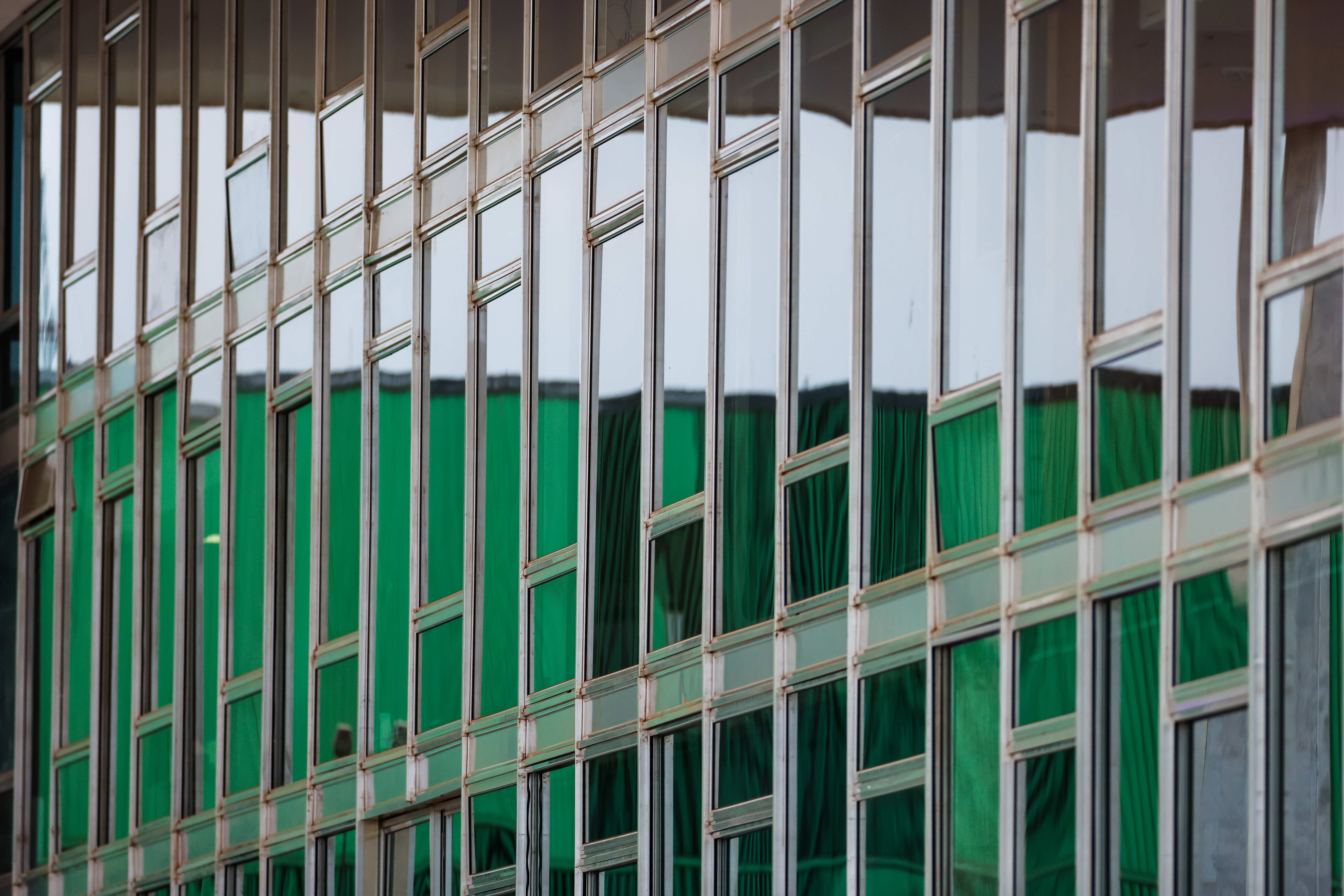 Foto colorida na horizontal mostra detalhe da fachada do STF formada por um conjunto de janelas de vidro dispostas em linhas e colunas.